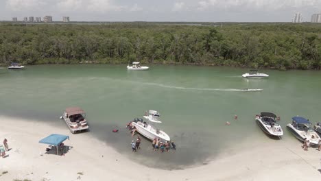 Orbiting-aerial,-local-Floridians-push-large-boat-off-sand-bar-beach