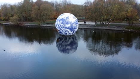 Luke-Jarram-Floating-Earth-Exhibition-Luftaufnahme-Im-Pennington-Flash-Park-Lake-Long-Pull-Away