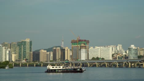 Hangang-River-Ferry-Cruise-Ship-with-Tourists-Sailing-along-Han-River-with-Picturesque-Seoul-City-Panorama---Landmark-Seoul-Namsan-Tower,-Mapodaegyo-bridge,-Gangbyeon-Expressway-Road,-Daytime-Summer