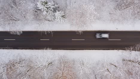 Car-from-above-is-driving-fast-over-a-wintry-road-with-snow-at-its-roof
