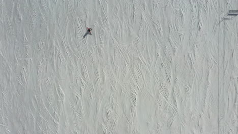 Person-skiing-down-hill-slope-fast,-aerial-top-down-follow-view