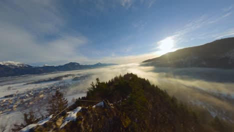 Toma-De-Drones-Fpv,-El-Paisaje-Cubierto-Bajo-La-Niebla-Con-Montañas-Circundantes-En-La-Mañana-En-Invierno-En-Eslovenia-Capturado-En-4k,-Drones-Volando-Rápido,-Cerca-De-Objetos-Con-Mucho-Movimiento