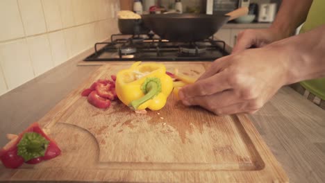 Red-And-Yellow-Capsicum-Chopped-In-Wooden-Board-In-Kitchen's-Countertop