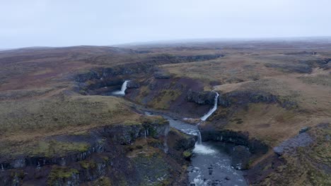 Aerial-flyover-volcanic-landscape-with-several-Waterfalls-flowing-into-Sela-River-during-foggy-day-on-Iceland