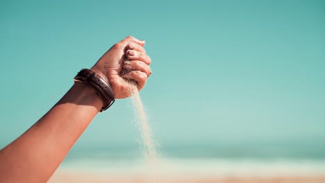 Closed-hand-releasing-sand-flowing-and-falling-through-fingers-and-fist-in-the-beach-during-a-sunny-summer-vacation-day