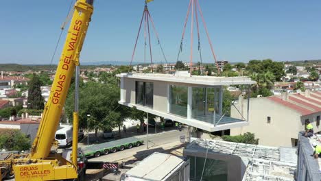 New-building-being-lifted-into-place-by-a-large-powerful-crane-in-an-urban-setting