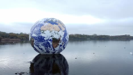 Luke-Jarram-floating-planet-earth-art-exhibit-aerial-view-at-Pennington-flash-lake-reverse-dolly-left