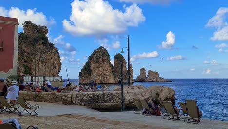 People-enjoying-blue-sea-of-Stacks-or-Faraglioni-of-Scopello-in-Sicily