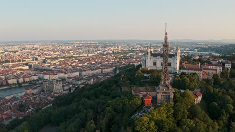 Establishing-circling-drone-shot-around-the-basilica-of-Lyon-and-transmitting-tower-France-at-sunset