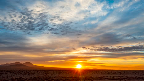 A-golden-sunrise-illuminates-the-Mojave-Desert-landscape-at-dawn-with-a-colorful-cloudscape-overhead---wide-angle-time-lapse