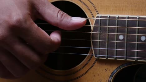 Close-up-front-shot-of-man's-hand-playing-guitar-with-picking-technic