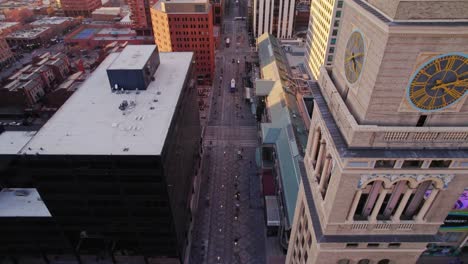 Drone-Aerial-View-Of-Arapahoe-Street-In-Downtown-Denver-Colorado-Flying-Backwards-Panning-Up-Showing-Lannies-Clock-Tower-During-Golden-Hour-Sunset