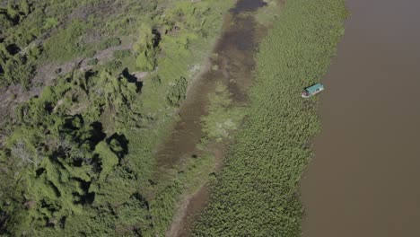 Pantanal---Drone-Filmando-Un-Lago-Con-Un-Bote-Entre-El-Agua-Y-La-Tierra
