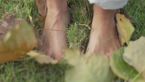 Weibliche-Füße-Stehen-Auf-Grünem-Gras-Und-Laub
