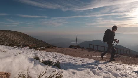 Front-view-of-Young-hiker-walking-up-a-Road-in-snowy-mountain-peak-in-Guadarrama-National-Park,-Madrid,-Spain