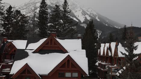 Wooden-house-rooftops-covered-in-snow-after-snowfall,-Foggy-mountain-background