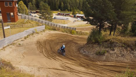 A-female-motocross-rider-drives-downhill-on-a-dirt-track,-filmed-from-above