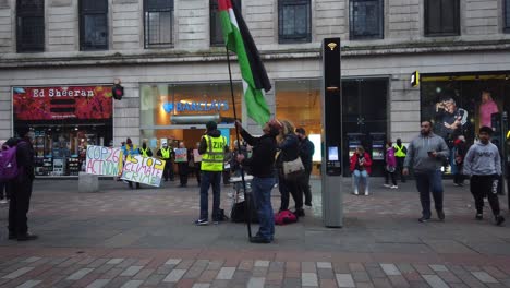 A-man-rising-the-Palestine-flag-in-a-busy-city-centre