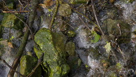 Small-stream-running-across-mossy-rocks-in-slow-motion