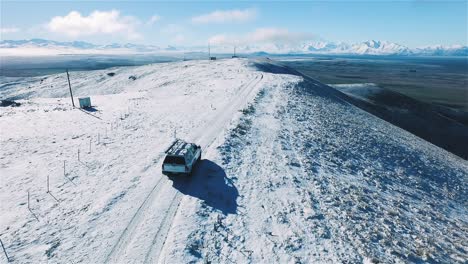 Wide-Shot-of-a-SUV-Car-Driving-on-Road-with-Snow-White-Mountains,-Mount-Mackenzie,-Mackenzie-Basin-Winter,-Aerial-tracking---Dolly-Shot