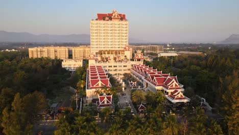 Hotel-Resort-Y-Spa-Exterior-órbita-Pan-Drone-Tiro-Durante-El-Amanecer-Con-Fondo-Montañoso-Rodeado-De-árboles-A-Lo-Largo-De-La-Playa-De-Cha-Am-En-Tailandia