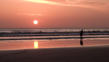 Sonnenuntergang-Am-Strand-Von-Playa-Maderas-In-Nicaragua-Mit-Einem-Mann,-Der-Steine-In-Die-Brandung-Wirft,-Weitwinkelaufnahme-Aus-Der-Hand