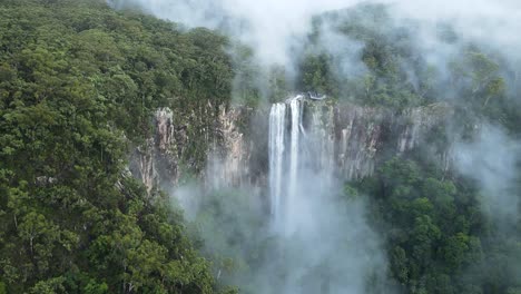 Filmischer-Blick-Auf-Einen-Nebelbedeckten-Berghang,-Der-Einen-Majestätischen-Wasserfall-Enthüllt,-Der-Sich-über-Die-Felswand-Aus-Rhyolith-Ergießt