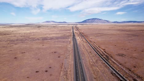 Drone-shot-over-a-desert-highway-with-a-semi-truck-and-car-driving