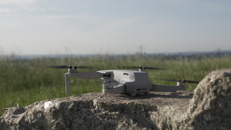 Drone-Quadcopter-Taking-Off-From-Rock-in-Countryside-Field-on-Sunny-Day-Close-Up