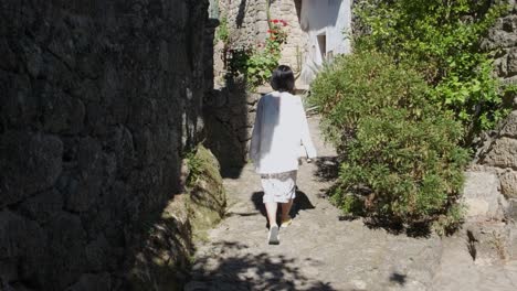 Back-view-of-unrecognizable-woman-walking-in-alley-of-Monsanto-historic-center,-Portugal