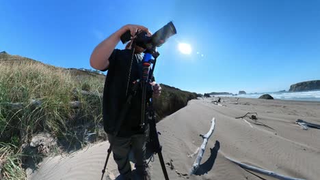 A-photographer-on-blue-sky-day-filming-at-Bandon-Beach