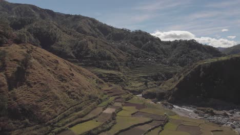 Terrace-fields-farms-vegetable-paddy-approaching-mountainous-community-revealing-valley-fast-aerial-wide-angle-in-kabayan-benguet-philippines