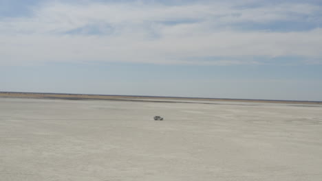 4x4-Auto-Fährt-Tagsüber-Auf-Der-Riesigen-Makgadikgadi-Salzpfanne-In-Der-Nähe-Der-Insel-Kubu-In-Botswana,-Südafrika