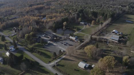 Drohnen-Luftaufnahme-Eines-Wunderschönen-Ackerlandes-Mit-Einem-Großen-Teich,-Einem-Wald-Und-Einer-Reihe-Alter-Gebäude-In-Der-Region-Ottawa