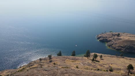 Small-boat-anchored-near-the-dry-and-rocky-shore-of-Okanagan-Lake-during-wildfire-season