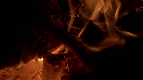 Close-up-of-the-red-hot-charcoal-and-flames-on-a-bonfire-at-night