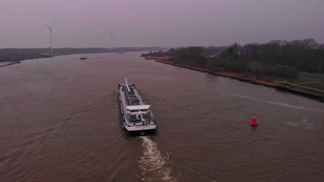 Aerial-Parallax-Behind-Stern-Of-Tanker-Ship-Travelling-Along-Oude-Maas-On-Overcast-Day