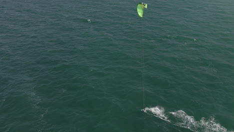 Aerial-view-of-kite-surfer-enjoying-windy-day-in-green-ocean-water