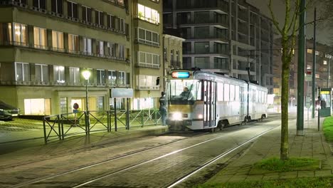 People-commuting-by-tramway-at-above-ground-metro-station-in-urban-Brussels-at-night---Time-Lapse
