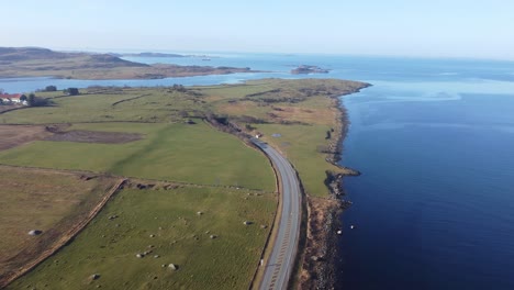 Road-E39-along-Norway-coast-is-surrounded-by-green-grasslands-and-going-down-into-subsea-tunnel-Byfjordtunnel---Stavanger-Rogaland-aerial