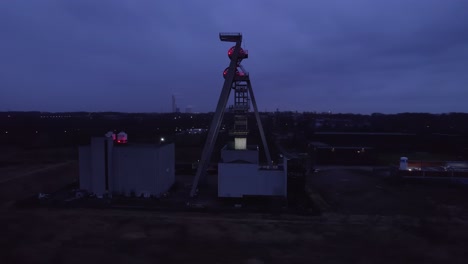 Disused-coal-mine-shaft-winding-tower-'"Zeche-Hugo"-illuminated-at-night,-drone-orbit