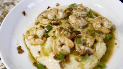 Sprinkling-chopped-green-onions-on-a-plate-of-shrimp-and-grits---dynamic-motion