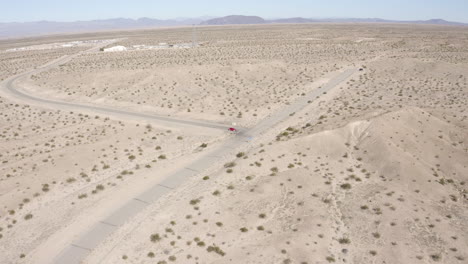 Aerial-view-following-a-red-car-driving-through-the-desert