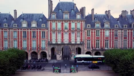 Autobús-De-La-Ciudad-Conduciendo-Por-La-Carretera-Alrededor-Del-Pabellón-De-La-Reina-En-Place-Des-Vosges,-París,-Francia