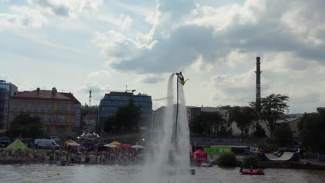 A-man-on-a-Flyboard-jet-pack-does-aerial-acrobatics-along-the-Naplavka-waterfront,-Prague,-Czech-Republic