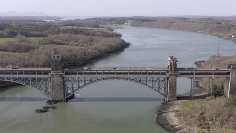 Aerial-view-of-the-Pont-Britannia-railroad-bridge,-flying-left-to-right-around-the-bridge-on-a-sunny-day,-Anglesey,-North-Wales,-UK