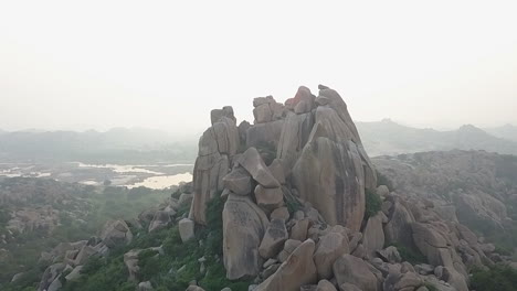 Orbiting-aerial-of-natural-rock-boulder-formation-in-foggy-Hampi-India