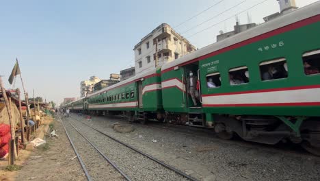 View-of-the-coaches-of-a-train-passing-through-a-city-market-with-buildings-on-the-side-of-the-track-in-Dhaka,-Bangladesh