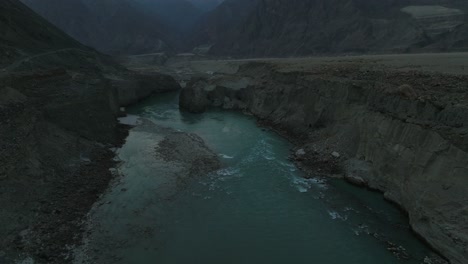 Aerial-Flying-Back-Turquoise-Colour-River-Water-In-Hunza-Valley-On-Dark-Moody-Overcast-Day