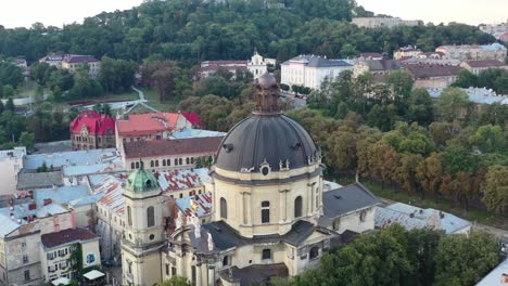 Drone-flying-over-the-dome-of-a-cathedral-in-Lviv-Ukraine-during-sunset-surrounded-by-European-buildings